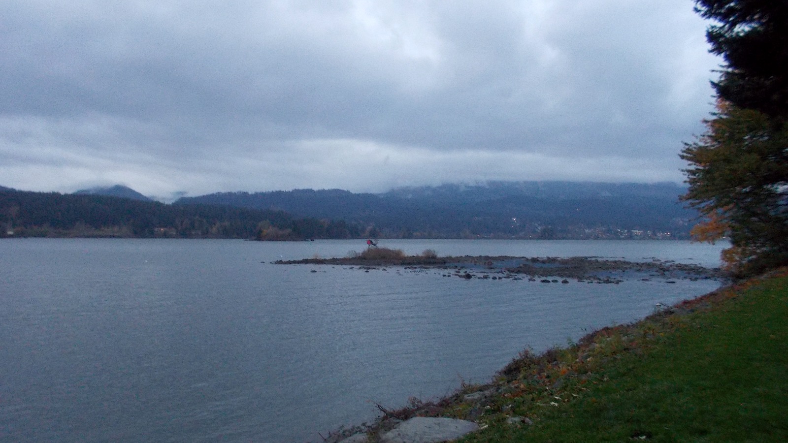 A cloudy view across the Columbia River from Cascade Locks with low forested hills beyond.
